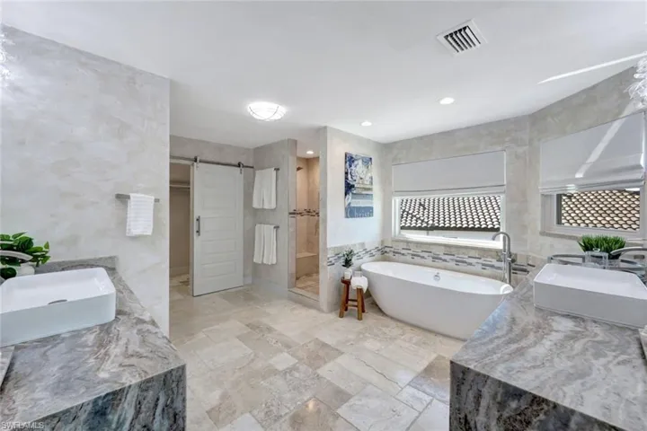 Bathroom with separate shower and tub, sink, and tile walls