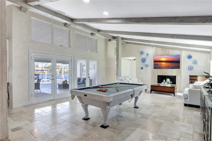 Recreation room with high vaulted ceiling, french doors, billiards, a premium fireplace, and beamed ceiling