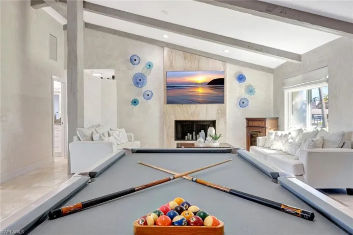 Playroom with a fireplace, lofted ceiling with beams, and pool table