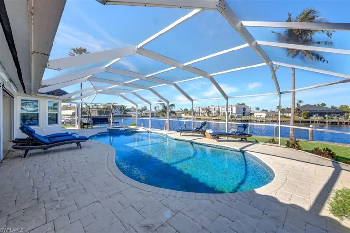 View of swimming pool with an in ground hot tub, a water view, glass enclosure, and a patio area