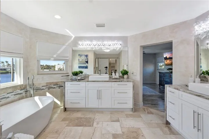 Bathroom featuring vanity, a tub to relax in, and tile walls