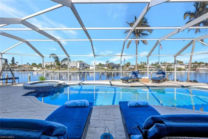 View of pool with a lanai, an in ground hot tub, and a water view