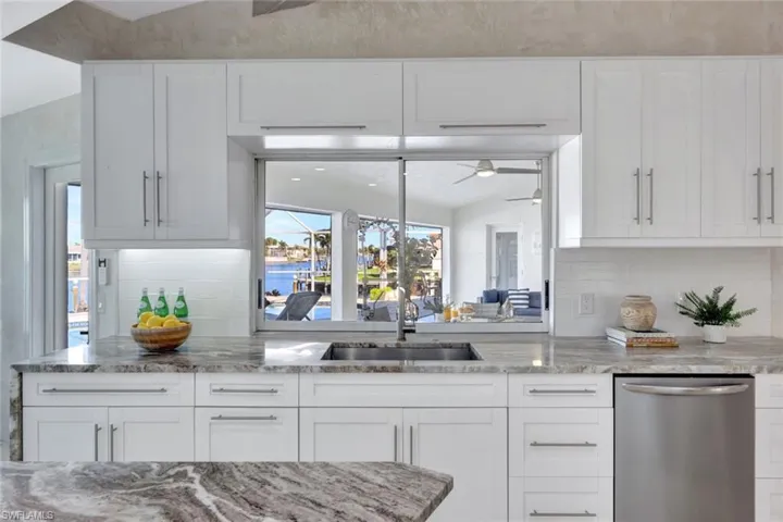 Kitchen with decorative backsplash, dishwasher, white cabinets, and sink
