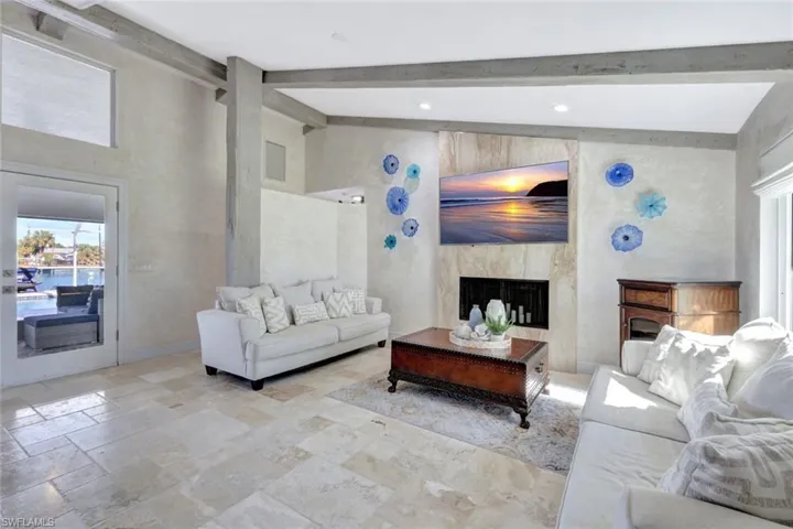 Living room featuring beam ceiling, a premium fireplace, and high vaulted ceiling
