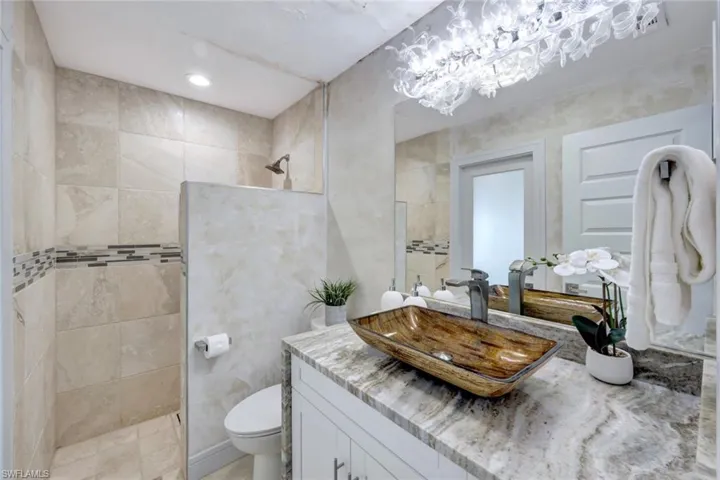 Bathroom featuring a tile shower, vanity, and toilet