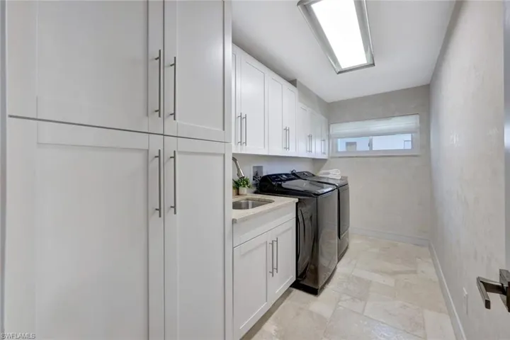 Washroom featuring washer and clothes dryer, cabinets, and sink