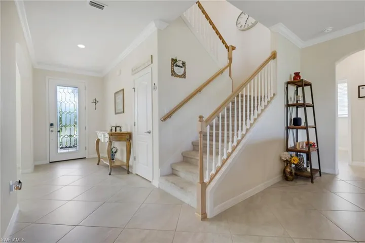 Foyer entrance featuring crown molding, arched walkways, and light tile patterned flooring