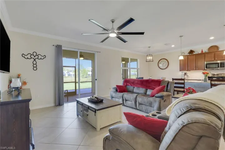 Living room with ceiling fan, ornamental molding, and light tile patterned floors
