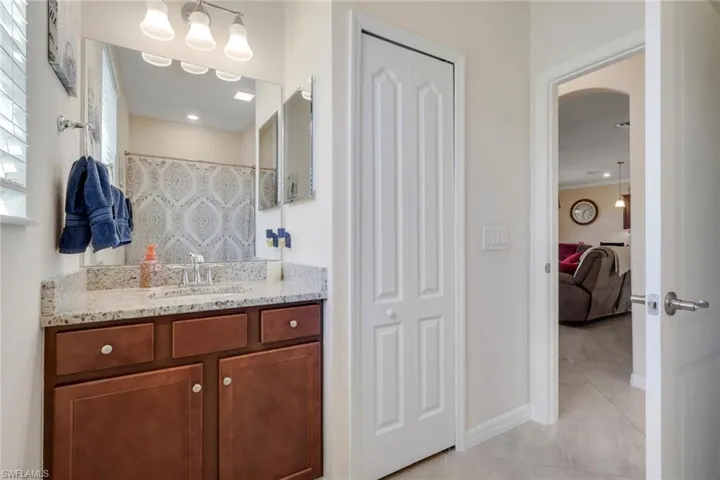Bathroom with vanity, a closet, a shower with shower curtain, light tile patterned flooring, and recessed lighting