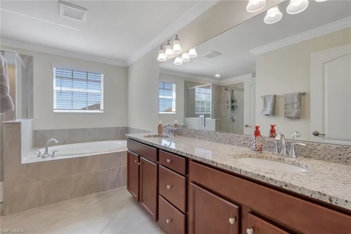 Full bath with a shower stall, a garden tub, double vanity, ornamental molding, and light tile patterned flooring
