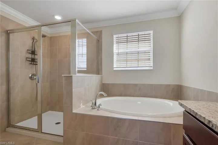 Full bathroom with a garden tub, a shower stall, vanity, and crown molding