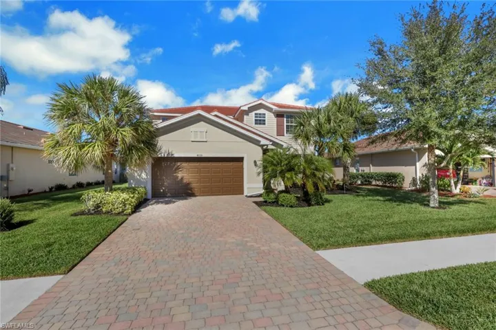 View of front of home featuring a front lawn, stucco siding, decorative driveway, and a garage
