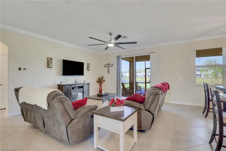 Living room featuring crown molding, arched walkways, ceiling fan, and light tile patterned flooring