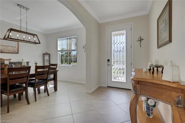 Foyer entrance with arched walkways, crown molding, and light tile patterned flooring