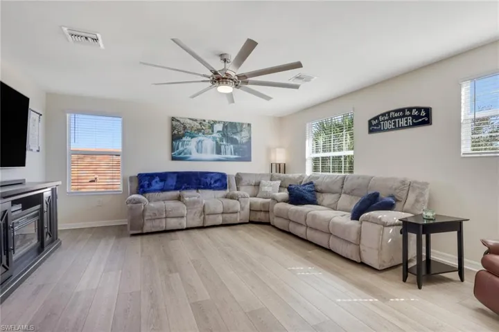 Living area featuring healthy amount of natural light, a ceiling fan, and light wood-style floors