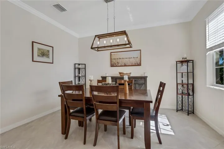 Dining area featuring ornamental molding and hanging lights