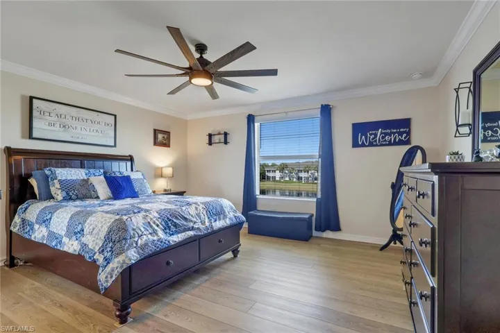 Bedroom with crown molding, light wood-style flooring, and a ceiling fan