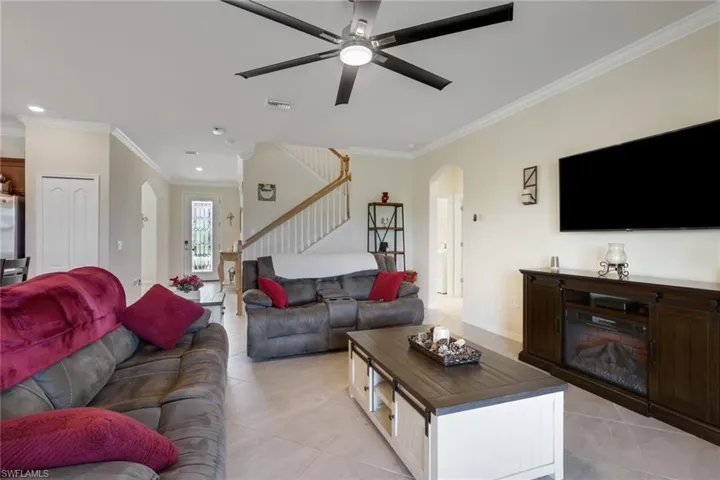 Living area featuring arched walkways, crown molding, a ceiling fan, light tile patterned floors, and recessed lighting