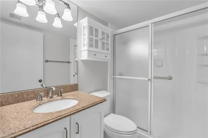 Bathroom with toilet, vanity, and walk in shower