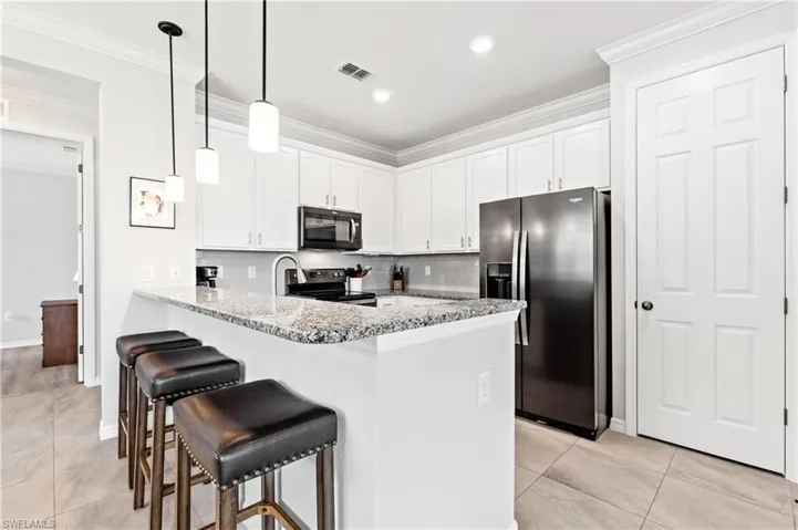 Kitchen featuring appliances with stainless steel finishes, white cabinetry, a peninsula, and ornamental molding