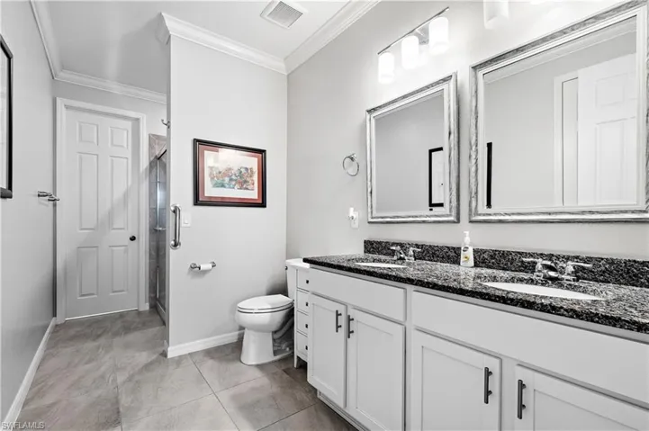 Full bath with crown molding, visible vents, a shower stall, and a sink