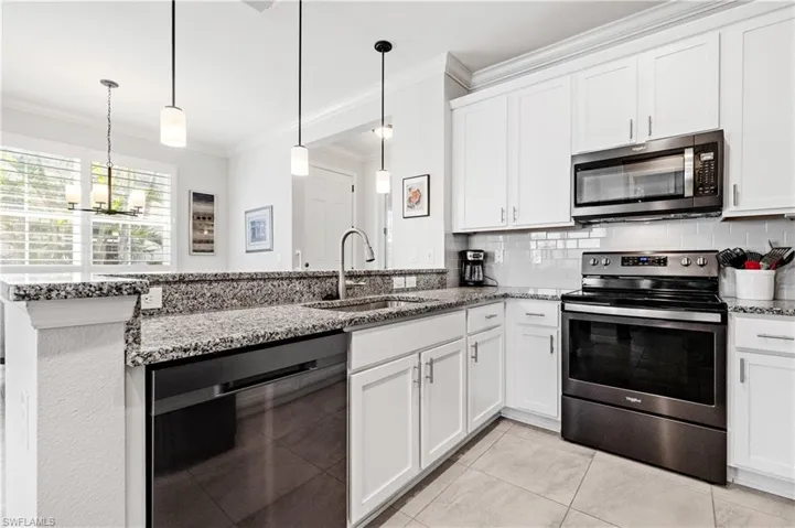 Kitchen with ornamental molding, decorative backsplash, appliances with stainless steel finishes, stone countertops, and a sink