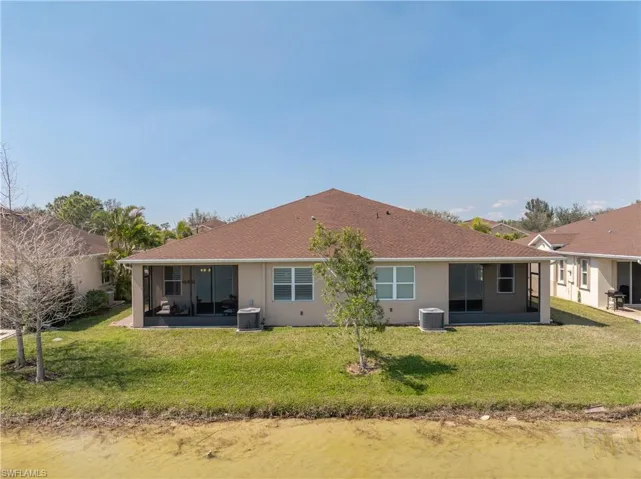 Back of house with central AC unit, stucco siding, a yard, and a sunroom