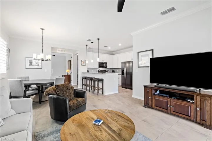 Living room featuring visible vents, baseboards, a chandelier, and crown molding