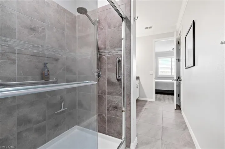 Bathroom featuring tile patterned floors, a stall shower, ornamental molding, ensuite bath, and baseboards