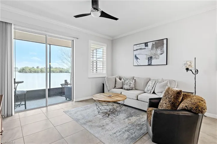 Living area featuring baseboards, a water view, ornamental molding, light tile patterned floors, and a ceiling fan