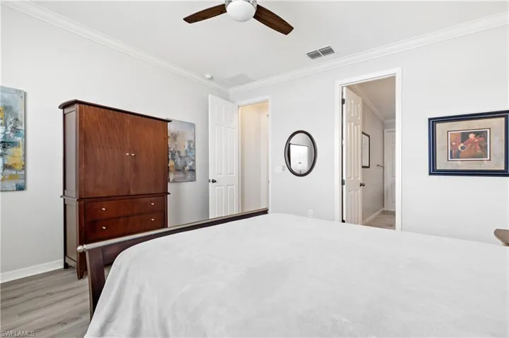 Bedroom with visible vents, crown molding, light wood finished floors, baseboards, and ceiling fan