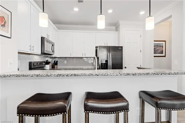 Kitchen featuring a peninsula, crown molding, tasteful backsplash, and stainless steel appliances