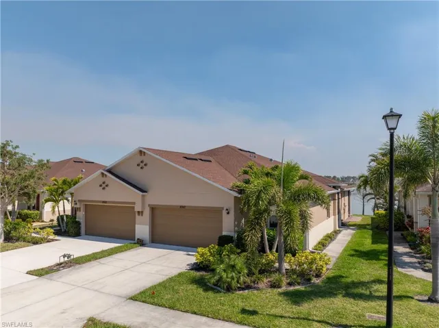 View of front of property with stucco siding, driveway, a front lawn, and an attached garage