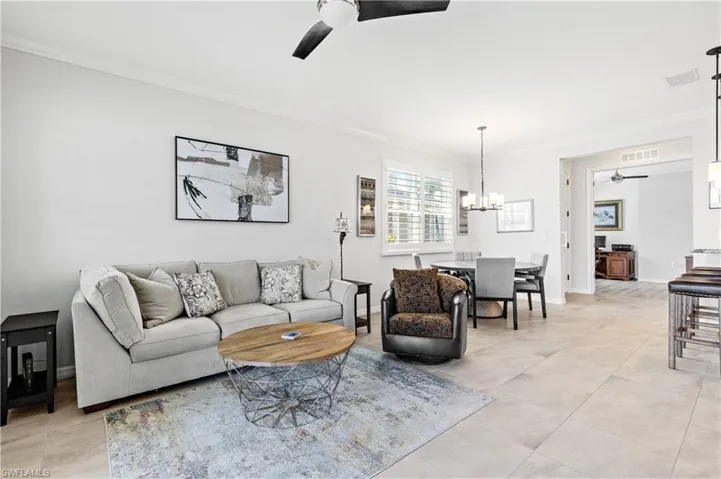 Living area with visible vents, ceiling fan with notable chandelier, and ornamental molding