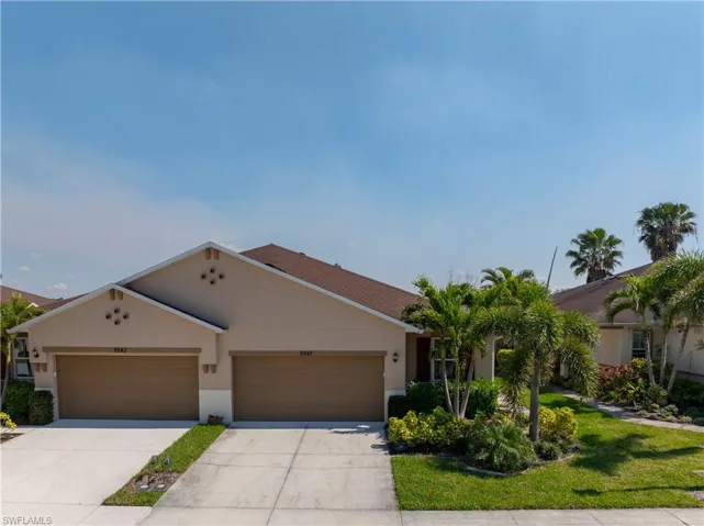 View of front of home with stucco siding, an attached garage, concrete driveway, and a front lawn