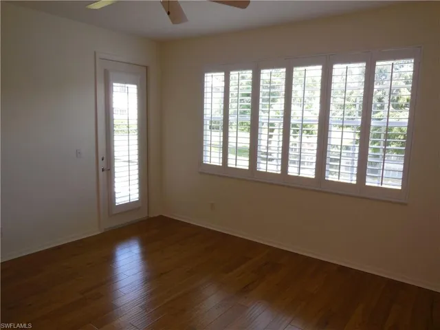 Empty room featuring a ceiling fan and dark wood-style flooring