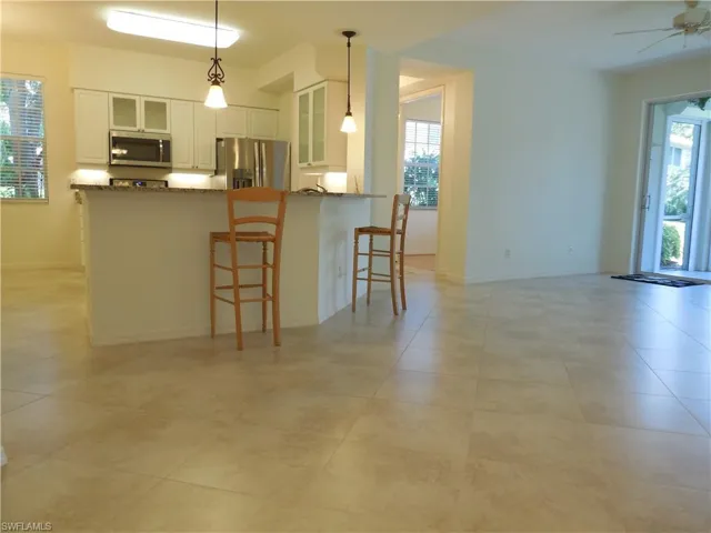 Kitchen with glass fronted cabinets, white cabinetry, a breakfast bar, stainless steel appliances, and ceiling fan