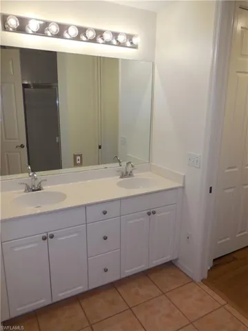 Full bath with double vanity and light tile patterned floors