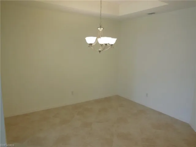 Unfurnished room with a tray ceiling and suspended lighting
