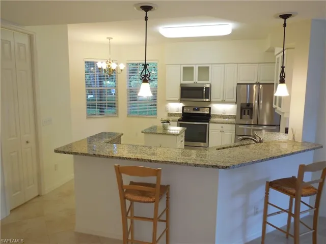 Kitchen with a breakfast bar, a peninsula, stainless steel appliances, and white cabinets