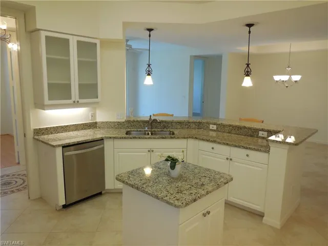 Kitchen with white cabinetry, a peninsula, light stone counters, and stainless steel dishwasher