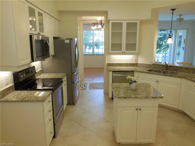 Kitchen with glass insert cabinets, ceiling fan, stainless steel appliances, white cabinets, and light stone counters