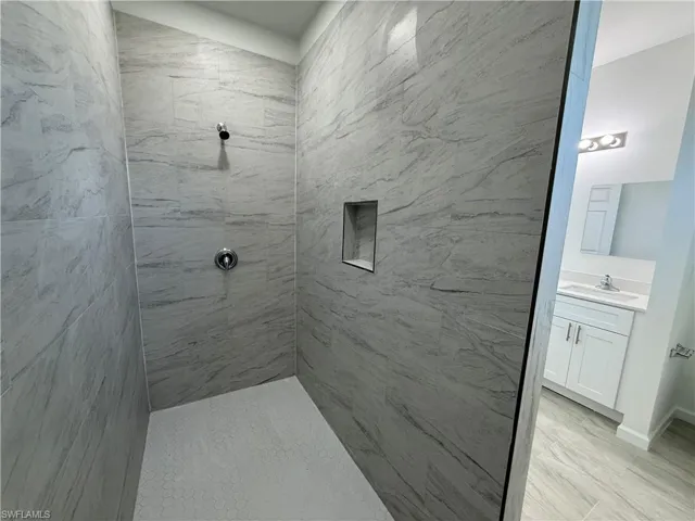 Bathroom with vanity and a marble finish shower