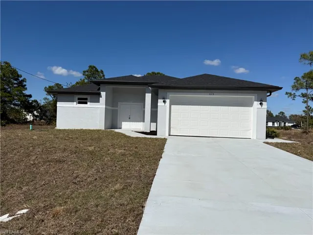 Prairie-style home featuring stucco siding, a garage, driveway, and a front lawn
