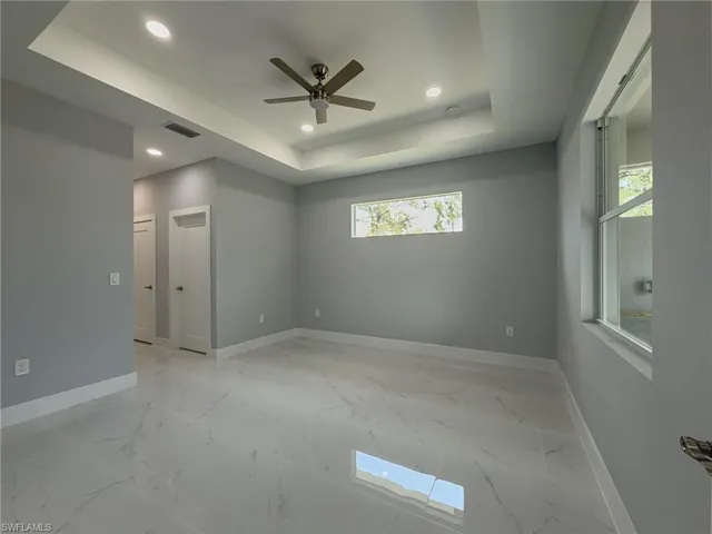 Master bedroom with recessed lighting, ceiling fan, a raised ceiling, visible vents, and baseboards