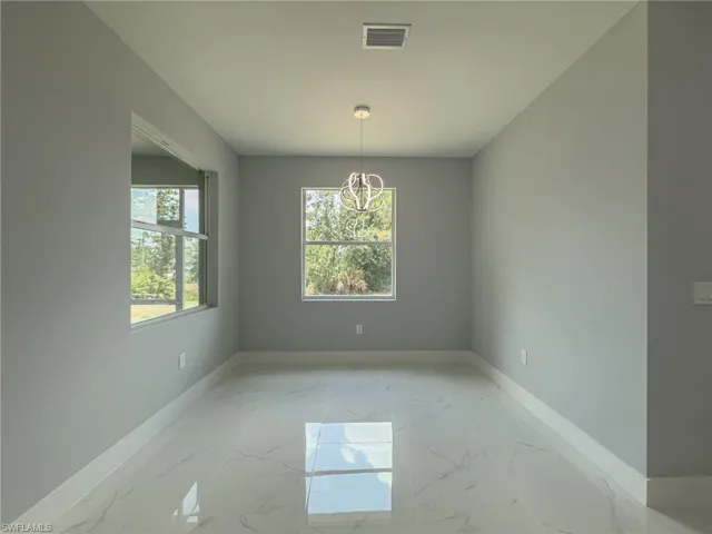 Unfurnished dining area with visible vents, a chandelier, marble finish floor, and baseboards