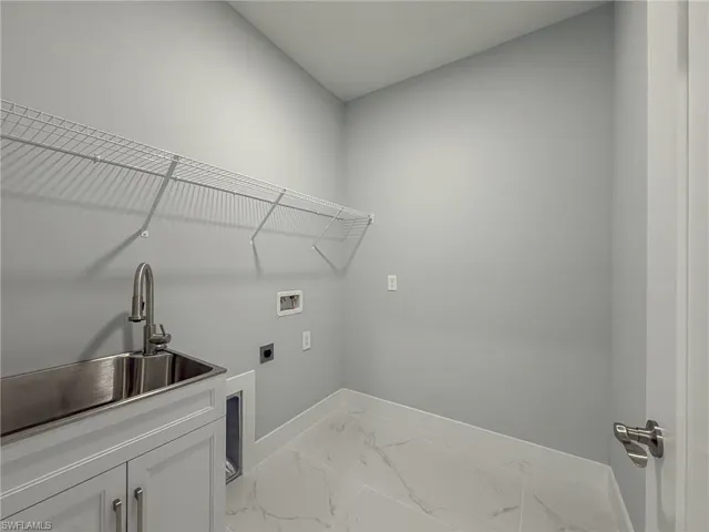 Laundry area with cabinet space, marble finish floor, washer hookup, a sink, and baseboards