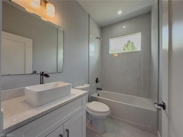 Bathroom featuring vanity, toilet,  shower combination, and marble finish floor