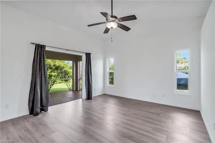 Spare room featuring lofted ceiling, light hardwood / wood-style flooring, and ceiling fan
