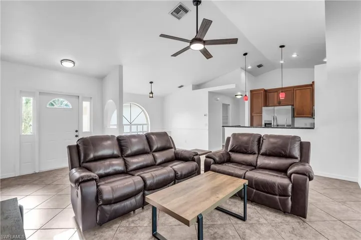 Tiled living room with vaulted ceiling and ceiling fan